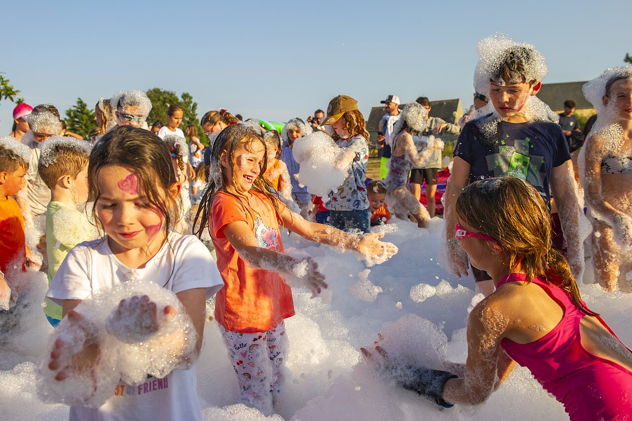 Vrolijke kinderen genieten van een schuimparty buiten op camping CAPFUN IJsselstrand in Doesburg.