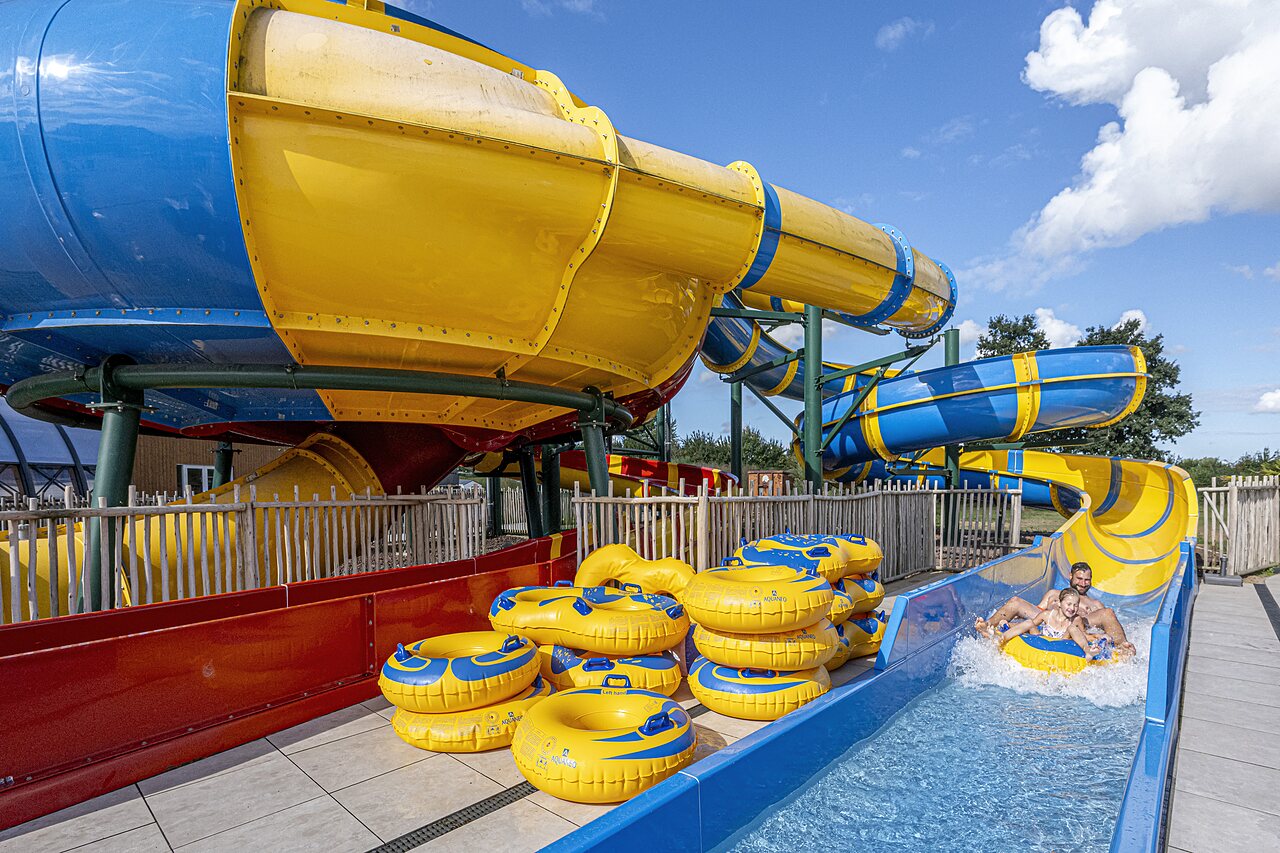 Reusachtige waterglijbanen en mensen op banden op camping CAPFUN IJsselstrand in Doesburg.