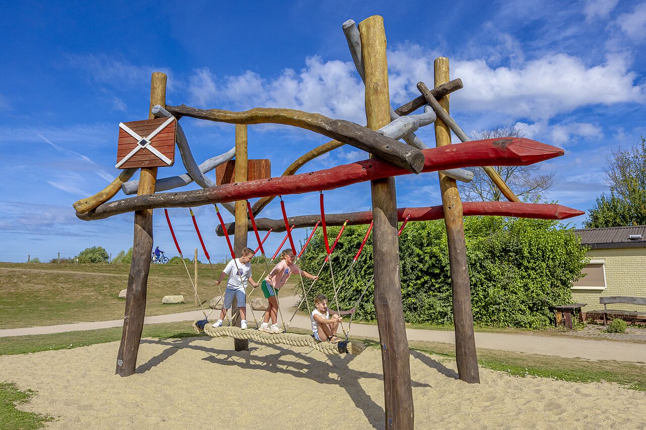 Kinderen spelen op houten en touwen speeltoestel op camping CAPFUN IJsselstrand in Doesburg.