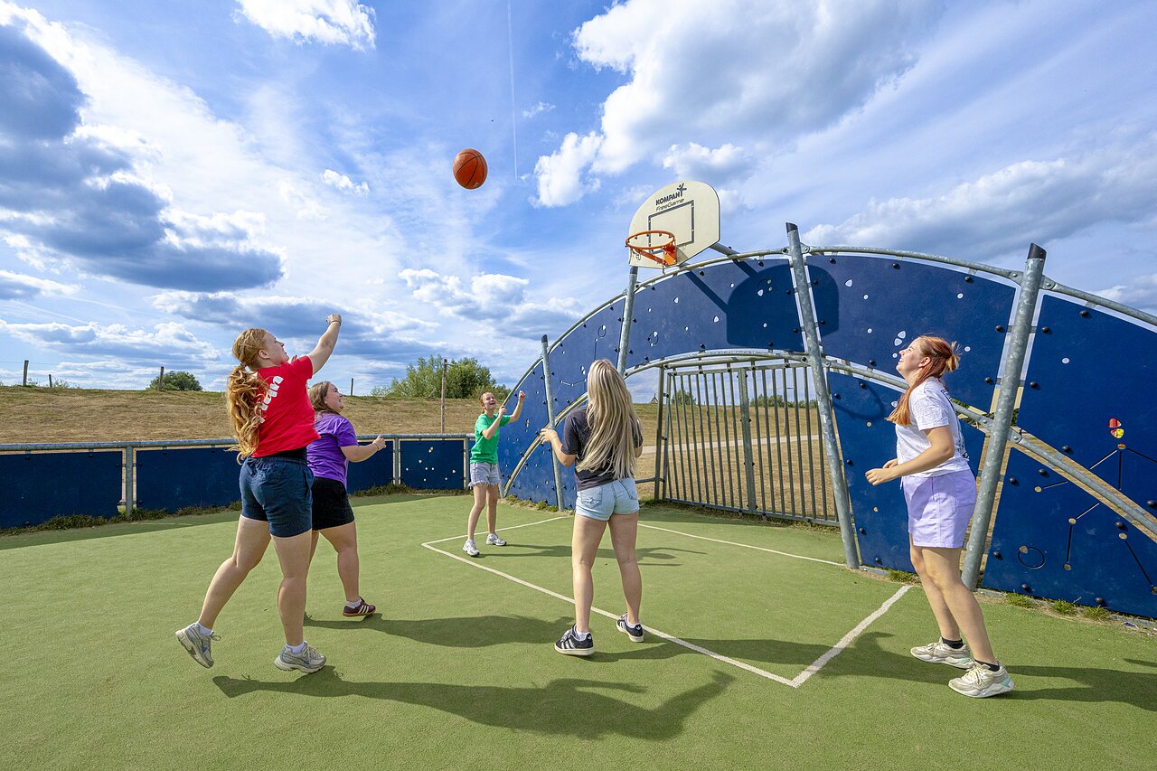 Jongeren basketballen op een multisportterrein bij camping CAPFUN IJsselstrand in Doesburg.