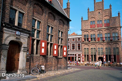 Historische straat in Doesburg met bakstenen gebouwen en levendige terrassen.