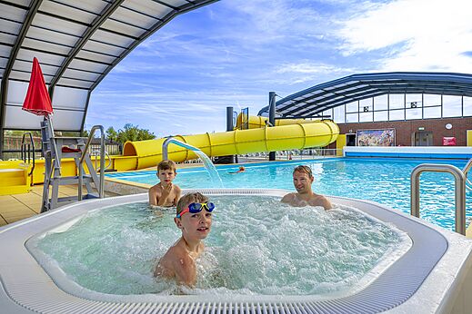 Bruisende jacuzzi, zwembad en gele glijbaan op camping CAPFUN IJsselstrand in Doesburg.