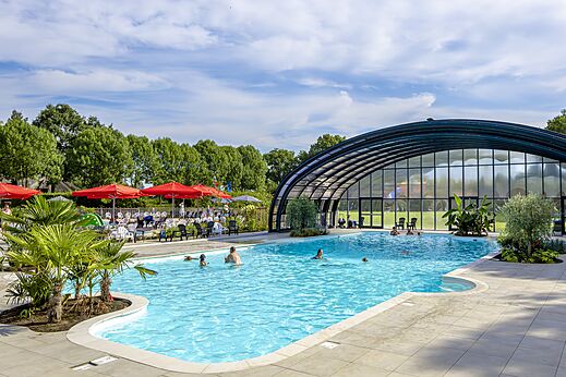 Buiten- en binnenzwembad met zwemmers op camping CAPFUN IJsselstrand in Doesburg.