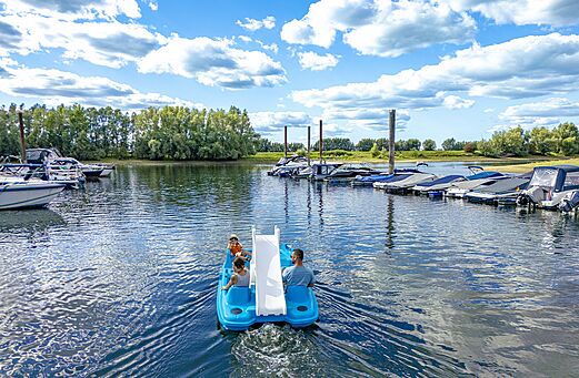 Waterfiets met glijbaan en familie op het water op camping CAPFUN IJsselstrand in Doesburg.
