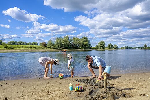 Familie bouwt zandkastelen op strand, camping CAPFUN IJsselstrand Doesburg.