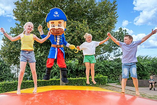 Kinderen en piratenmascotte springen op springkussen op camping CAPFUN IJsselstrand in Doesburg.