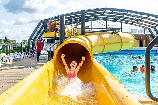 Gele waterglijbaan en buitenzwembad op camping CAPFUN IJsselstrand in Doesburg.
