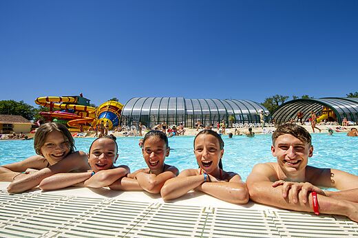 Lachende familie in het zwembad met glijbanen op camping CAPFUN Imbours in LARNAS (07).