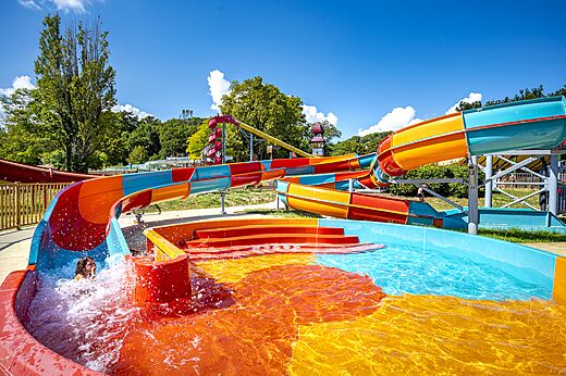 Kleurrijke waterglijbanen en zwembad op camping CAPFUN Imbours in LARNAS (07).