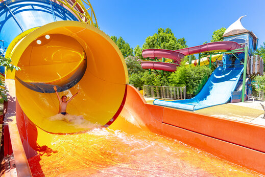 Reusachtige waterglijbaan met lachend kind op camping CAPFUN Jantou in LE THOR (84).