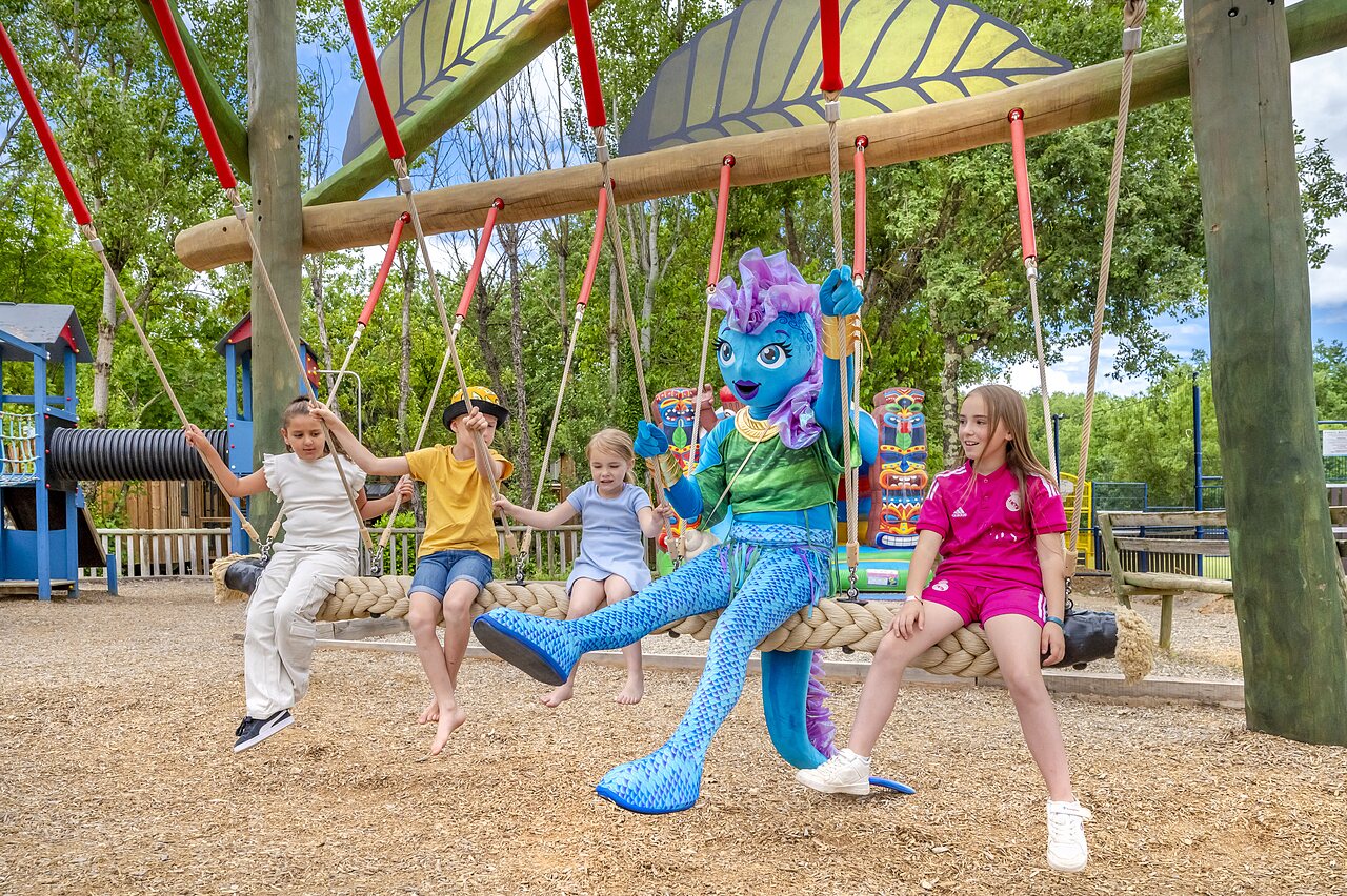 Kinderen en mascotte op reuzenschommel op camping VAGUES OCEANES Labeiller in Saint Victor de Malcap (30).