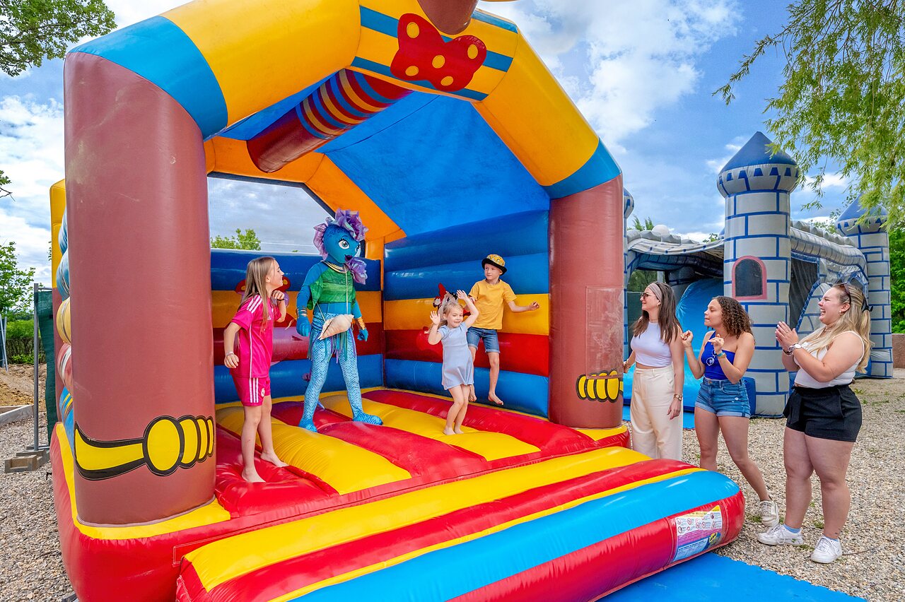 Kinderen en mascotte op kleurrijk springkasteel op camping VAGUES OCEANES Labeiller.