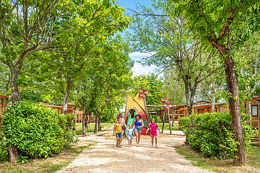 Kleurrijke speeltuin met glijbaan en schaduwrijke stacaravans op camping VAGUES OCEANES Labeiller in Saint Victor de Malcap.