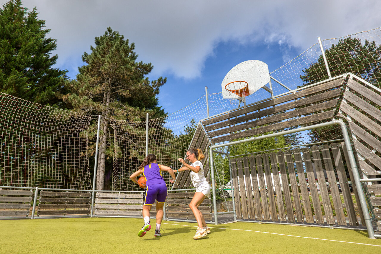 Jonge vrouwen basketballen op multisportterrein bij camping CLICOCHIC Lac de Miel.