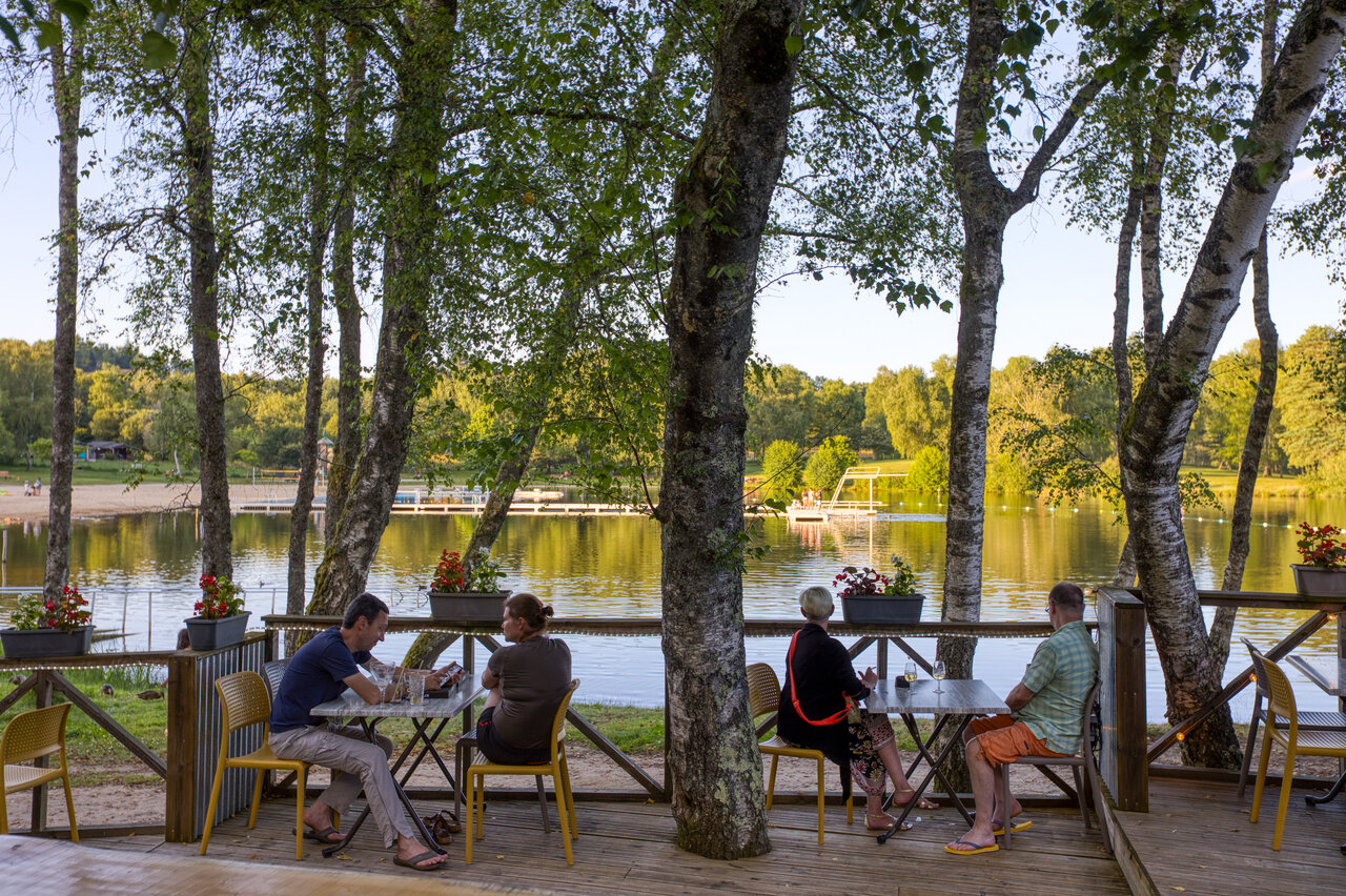 Schaduwrijk restaurantterras, meer, strand op camping CLICOCHIC Lac de Miel.