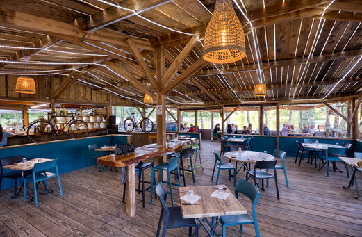 Houten restaurant en bar met uitzicht op het meer op camping CLICOCHIC Lac de Miel in Beynat (19).