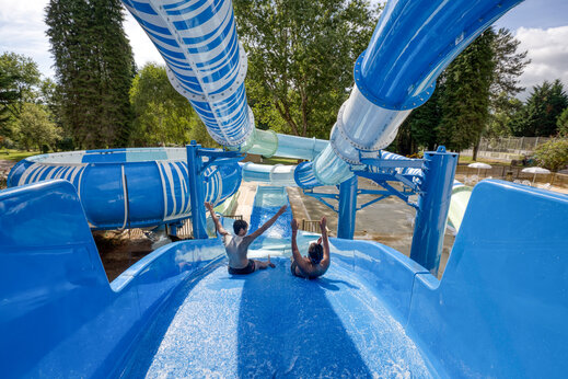 Blauwe waterglijbanen, kinderen vermaken zich op camping CLICOCHIC Lac de Miel in Beynat.