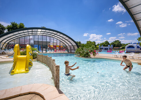 Buitenzwembad, gele glijbaan en kinderen op camping CAPFUN Lac de Ribou.