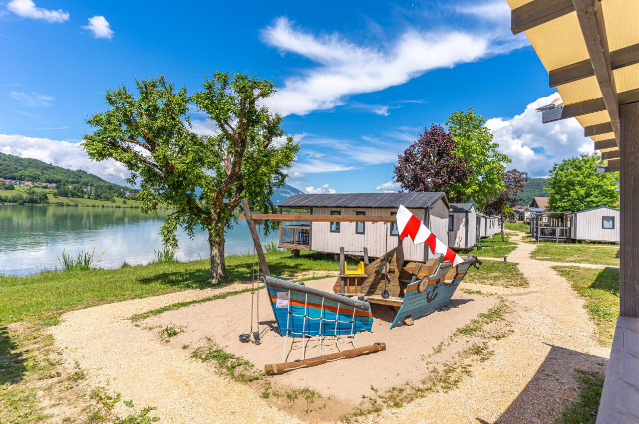 Speeltuin boot, meer en stacaravans op camping CLICOCHIC Lac du Lit du Roi in Massignieu-de-Rives (01).