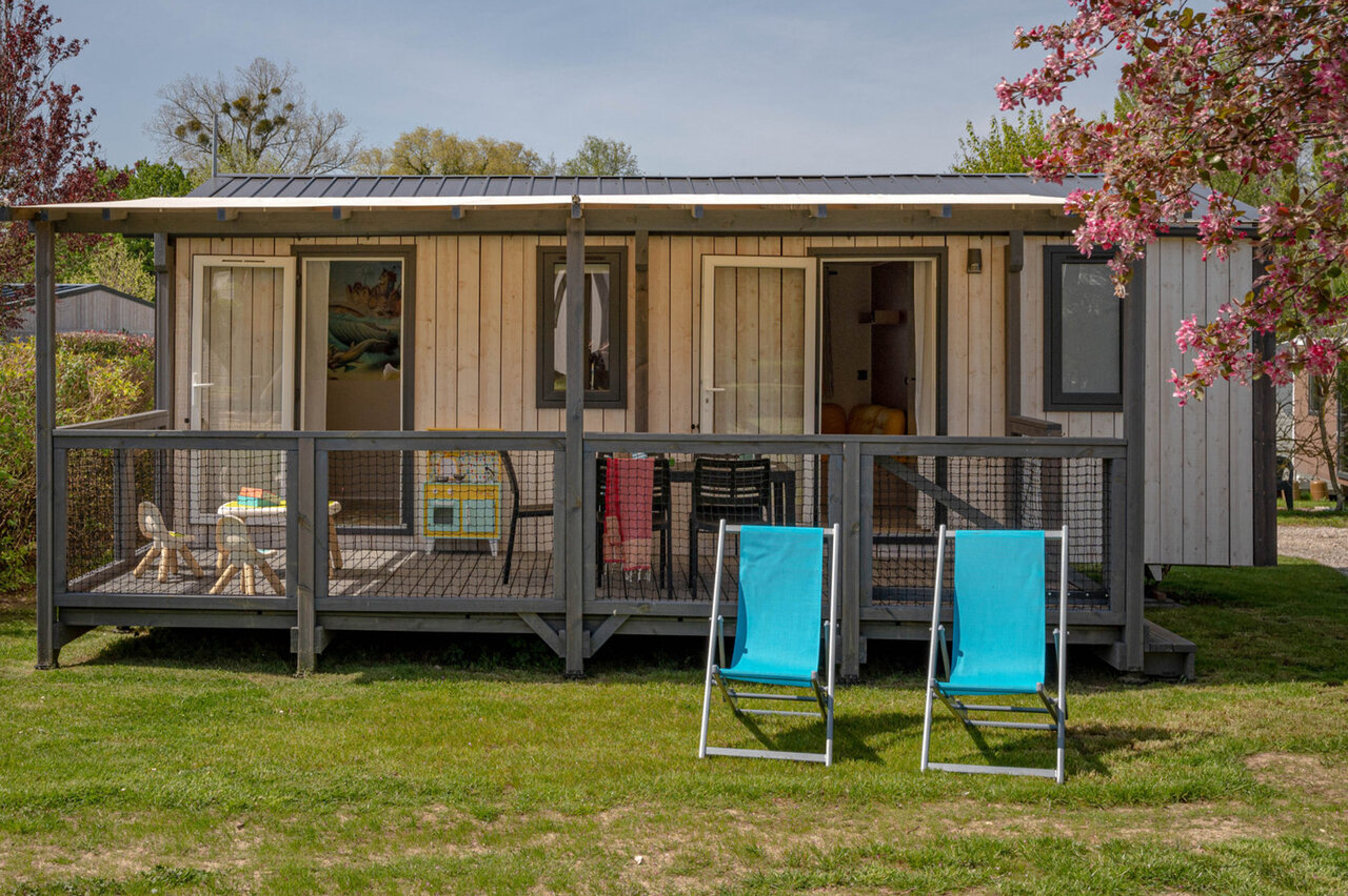 Moderne stacaravan met overdekt terras en ligstoelen op camping CLICOCHIC Lac du Lit du Roi in Massignieu-de-Rives (01).