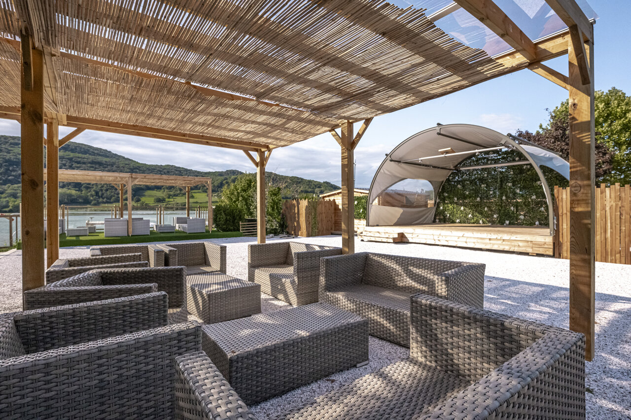 Buitenlounge, podium, uitzicht meer op camping CLICOCHIC Lac du Lit du Roi in Massignieu-de-Rives (01).