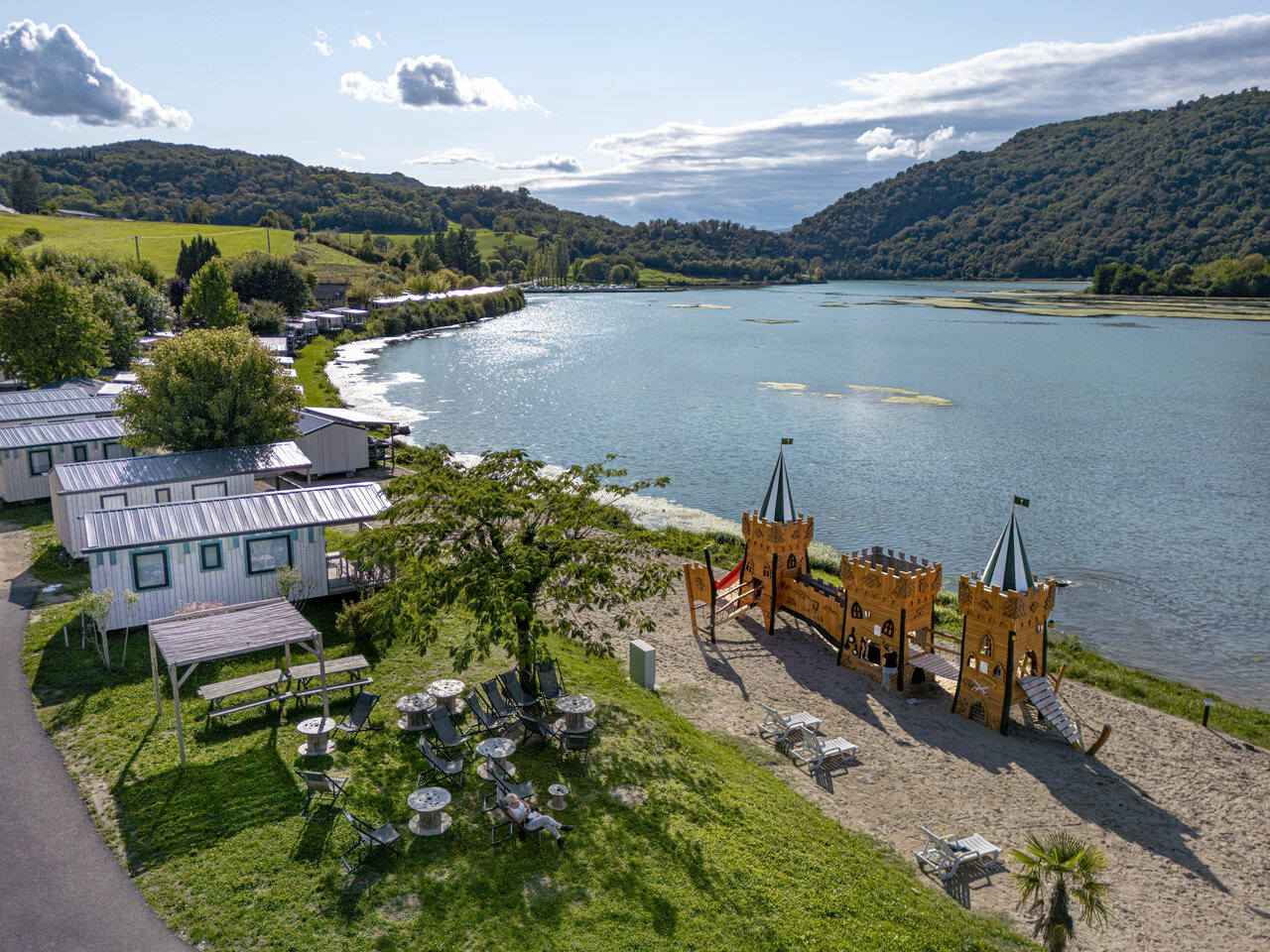 Luchtfoto van het meer, stacaravans en speeltuin op camping CLICOCHIC Lac du Lit du Roi in Massignieu-de-Rives (01).