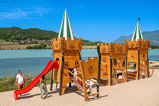 Houten kasteel speeltuin met rode glijbaan op camping CLICOCHIC Lac du Lit du Roi in Massignieu-de-Rives (01).
