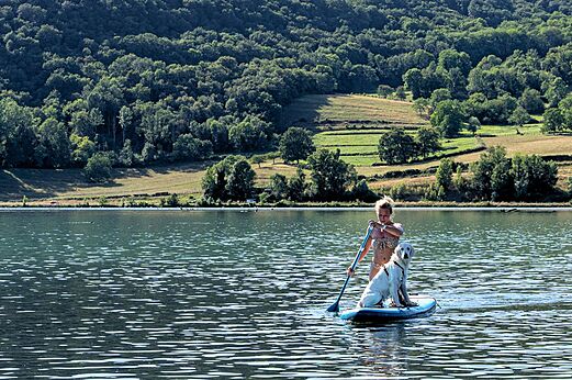 Stand-up paddle met hond op het meer op camping CLICOCHIC Lac du Lit du Roi in Massignieu-de-Rives (01).