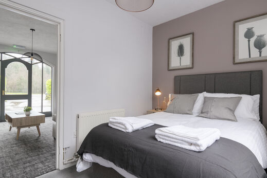 Comfortabele slaapkamer met groot tweepersoonsbed en moderne inrichting op camping CAPFUN UK Lakeview Manor in Dunkeswell.