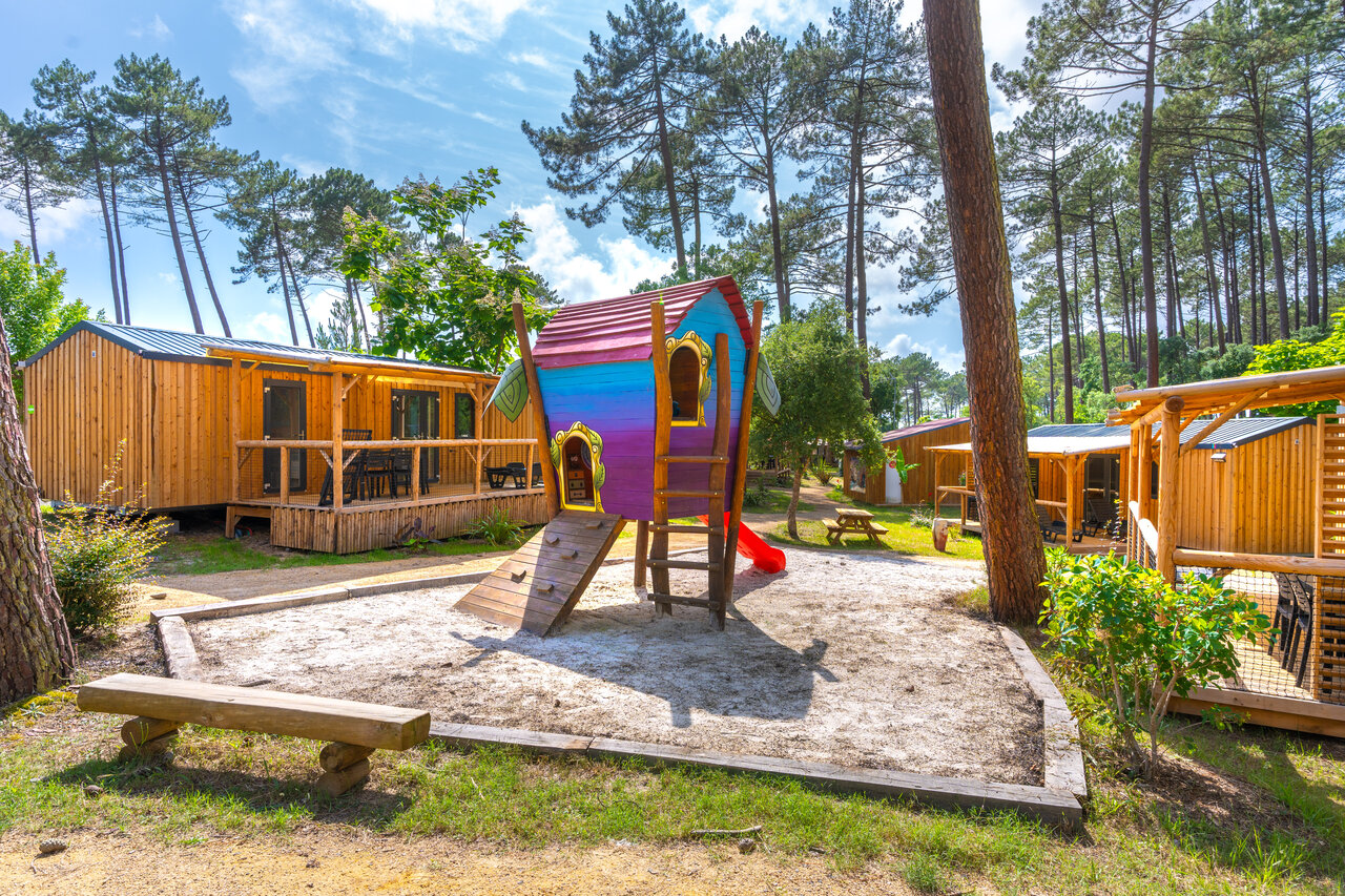 Kinderspeeltuin met kleurrijk huisje en stacaravans op camping CAPFUN Landisland in Moliets-et-Maa (40).