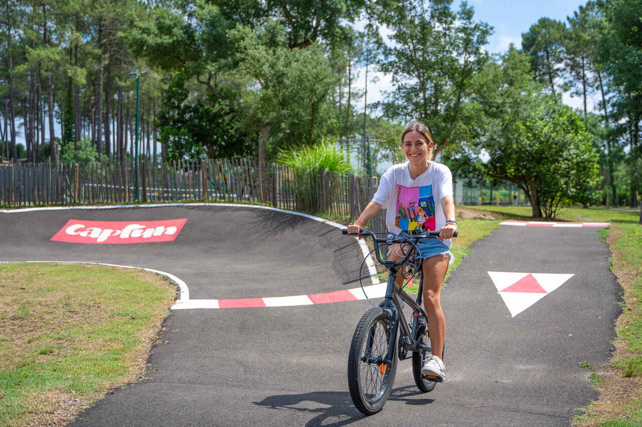 Jonge vrouw op pumptrack met fiets op CAPFUN Landisland in Moliets-et-Maa.
