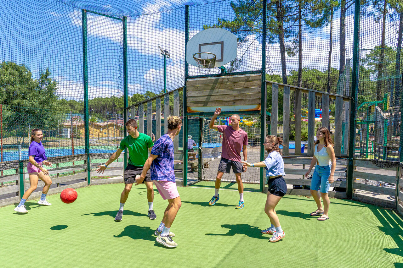 Jongeren spelen basketbal op het multisportterrein van camping CAPFUN Landisland in Moliets-et-Maa.