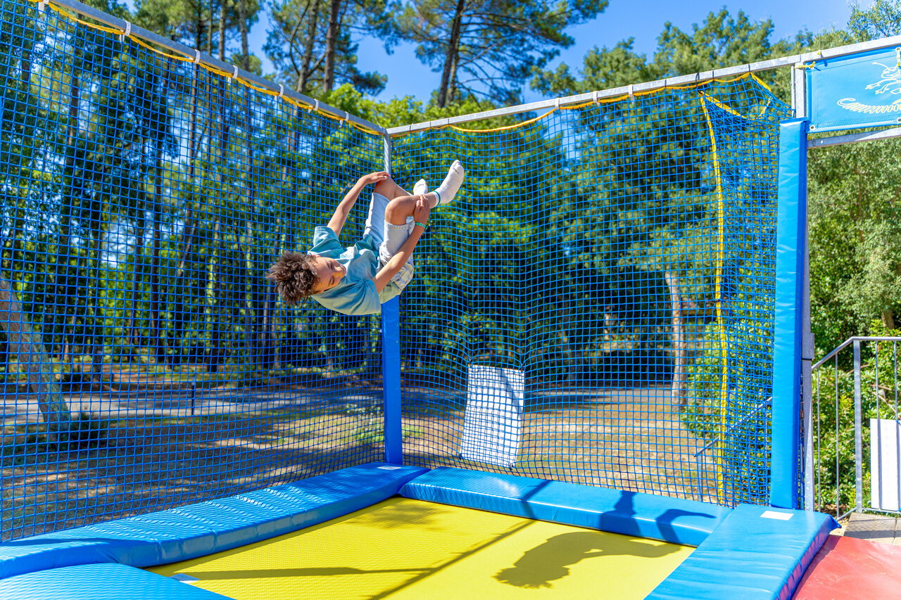Kind springt op veilige trampoline met net op camping CAPFUN Landisland in Moliets-et-Maa (40).
