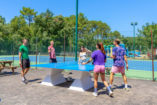 Vrienden spelen tafeltennis buiten op camping CAPFUN Landisland Moliets-et-Maa.