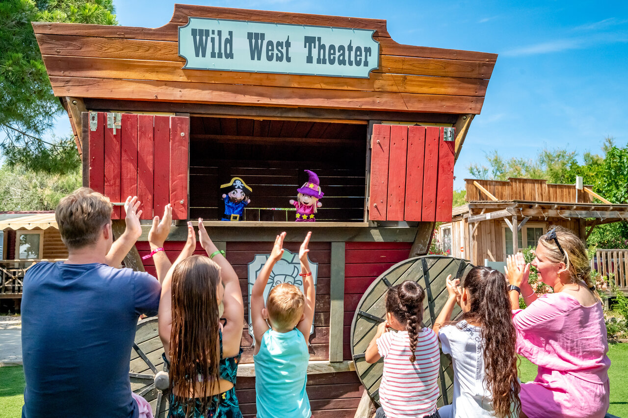 Poppenkastvoorstelling in het Wild West Theater, familie applaudisseert op camping CAPFUN Las Bousigues in Le Barcar�s (66).