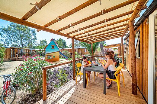Familie luncht op terras van een stacaravan met speeltuin op camping CAPFUN Las Bousigues in Le Barcarès (66).
