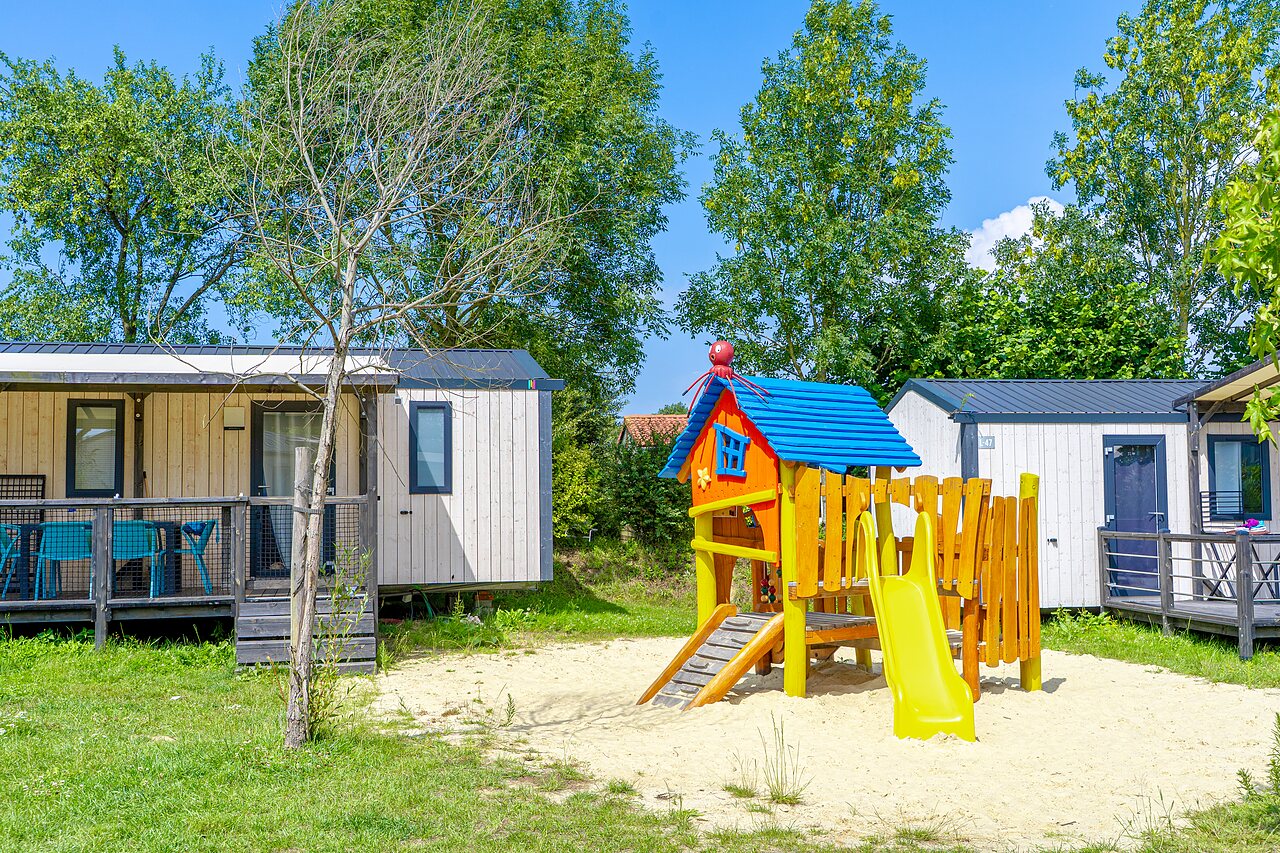 Kleurrijke speeltuin en moderne stacaravans op camping VAGUES OCEANES Les Iles in Hudimesnil (50).