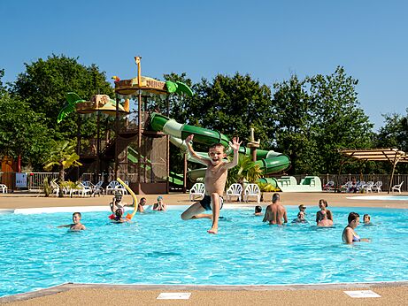 Kind springt in zwembad met glijbanen op camping CLICOCHIC Les Secrets de Padirac.