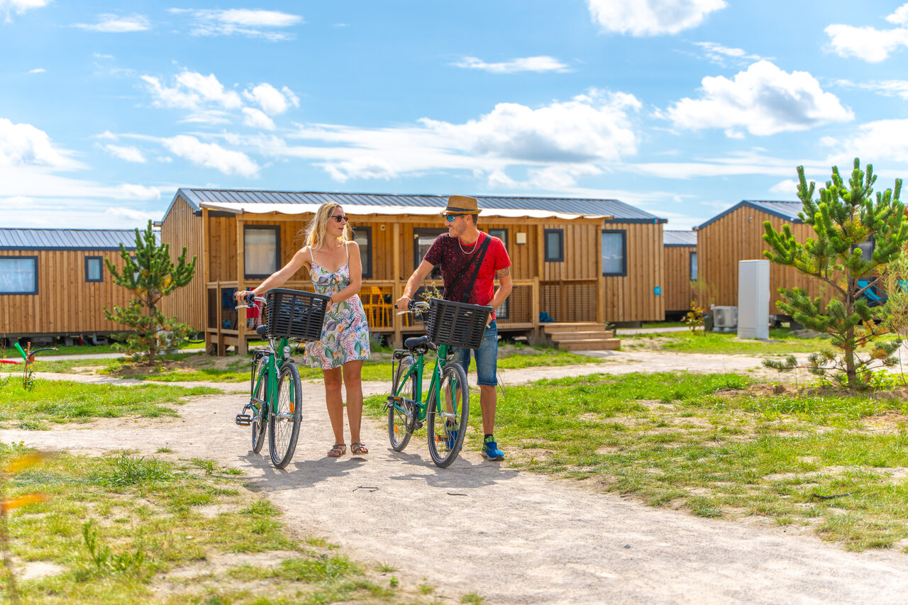 Koppel met fietsen voor moderne stacaravans, camping VAGUES OCEANES Licorne in Duinkerke (59).