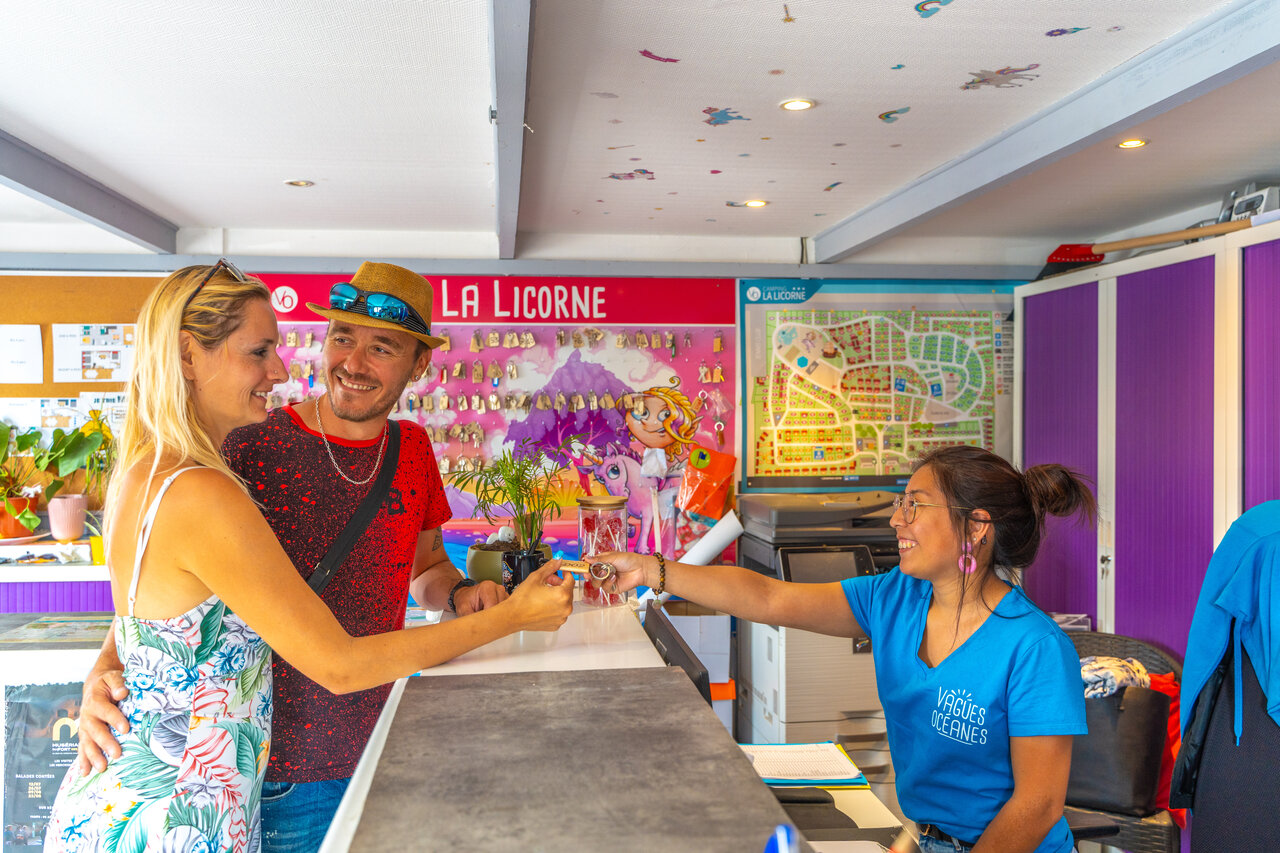 Koppel ontvangt sleutels bij receptie camping VAGUES OCEANES Licorne.