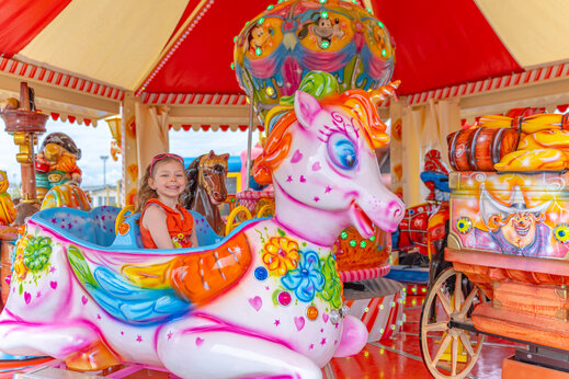 Lachend meisje op kleurrijke eenhoorn draaimolen camping VAGUES OCEANES Licorne Duinkerke (59).