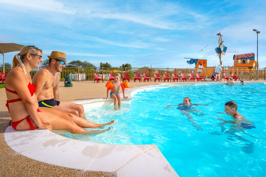 Familie en kinderen genieten van het zwembad met waterspelen op camping VAGUES OCEANES Licorne in Duinkerke (59).