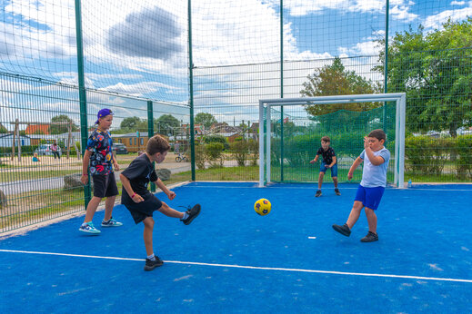 Kinderen voetballen op het multisportterrein bij camping VAGUES OCEANES Licorne in Duinkerke (59).