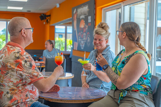 Lachende gasten met cocktails in de bar van camping VAGUES OCEANES Licorne in Duinkerke (59).