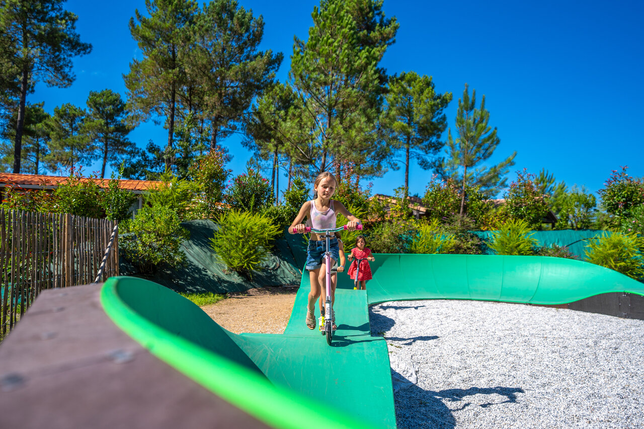 Kinderen op scooters op groene pumptrack op camping CAPFUN Lila in LINXE (40).