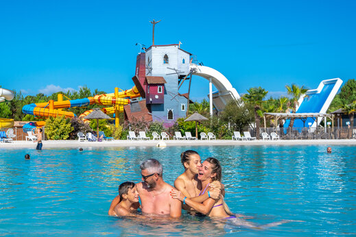 Blije familie in zwembad met reuzenglijbanen op camping CAPFUN Lila in LINXE (40).
