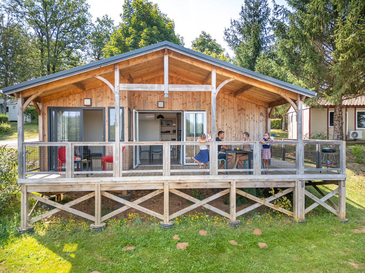 Houten chalet met terras en familie op camping CLICOCHIC Linotte, Le Bugue (24).