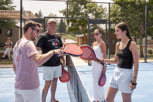 Lachende familie padel spelend op het multisportterrein van camping CLICOCHIC Linotte in Le Bugue (24).