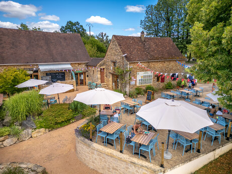 Buitenterras van restaurant en bar met parasols op camping CLICOCHIC Linotte in Le Bugue (24).