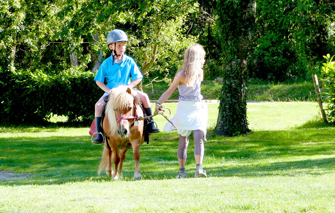 Kind op pony, begeleid door begeleider op camping CAPFUN Lodge in SARZEAU (56)